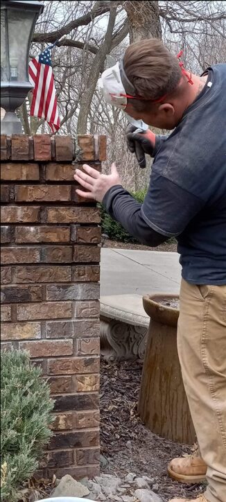 Mason building a brick pillar course by course in Omaha
